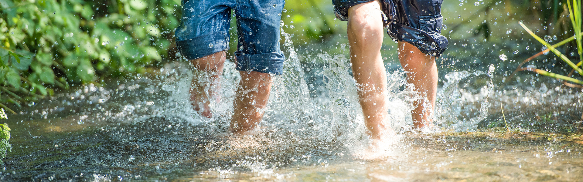 Kinder rennen durch klares Wasser eines Bachs