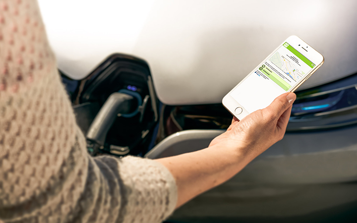 Fahrer überprüft Ladestatus seines E-Fahrzeugs mit App