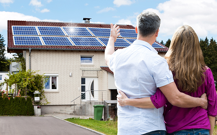 Paar vor Haus mit PV-Anlage