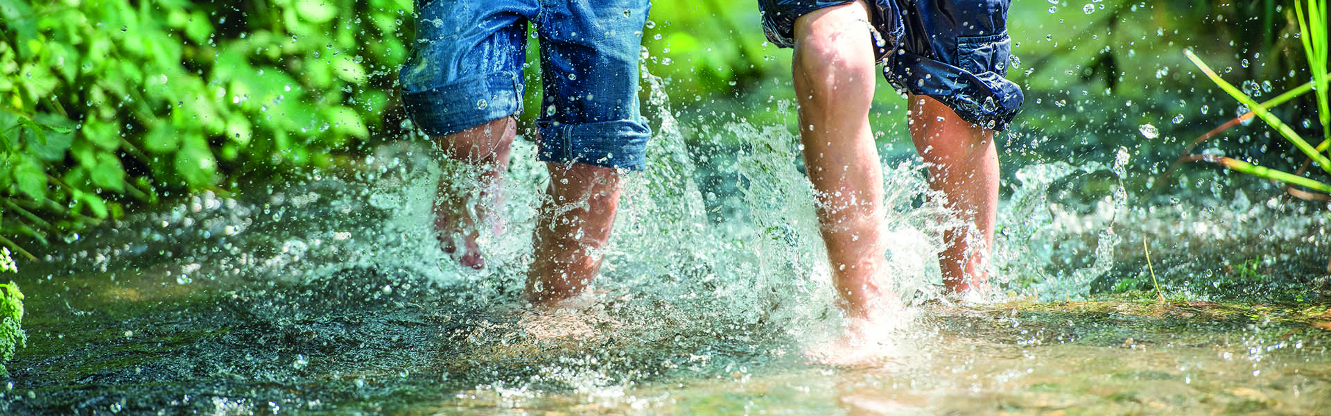 Kinder rennen durch klares Wasser eines Bachs.