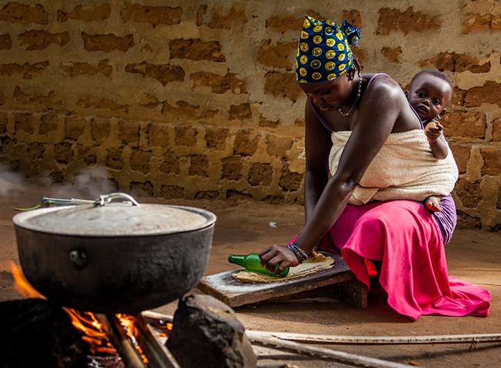 Mutter mit Kind kocht in Hütte in Kenia
