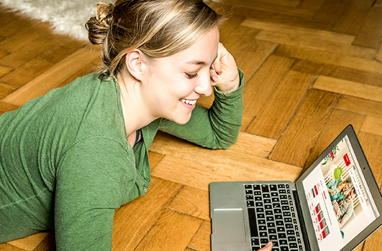 Frau sitzt vor Laptop und surft im Internet